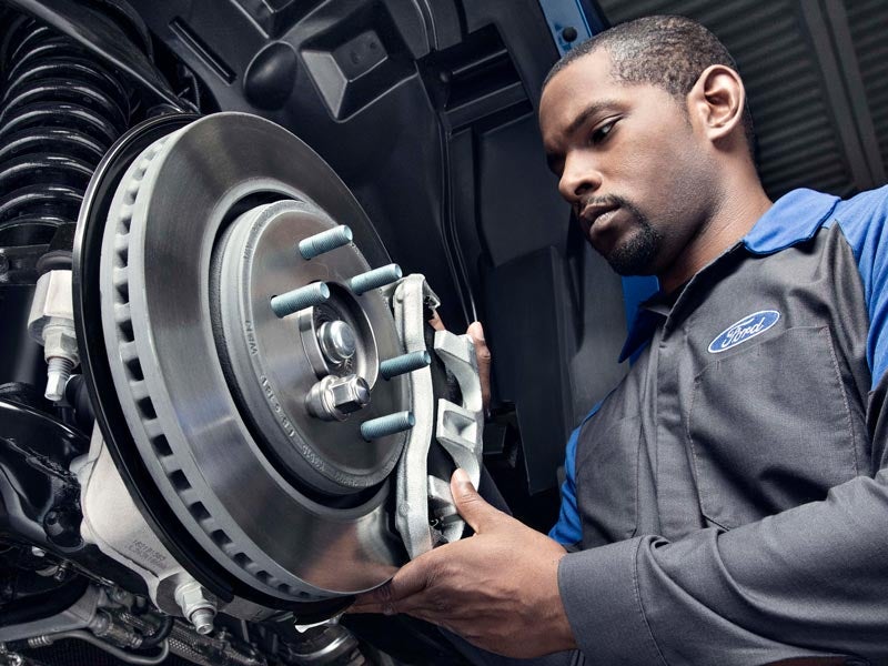 Technician inspecting or installing a brake rotor on a Ford vehicle