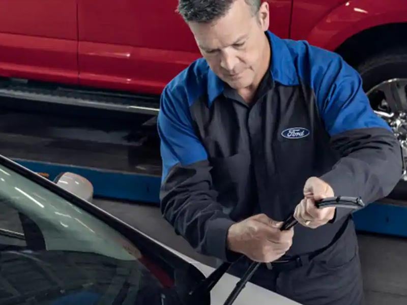 Technician replacing a windshield wiper on a Ford vehicle