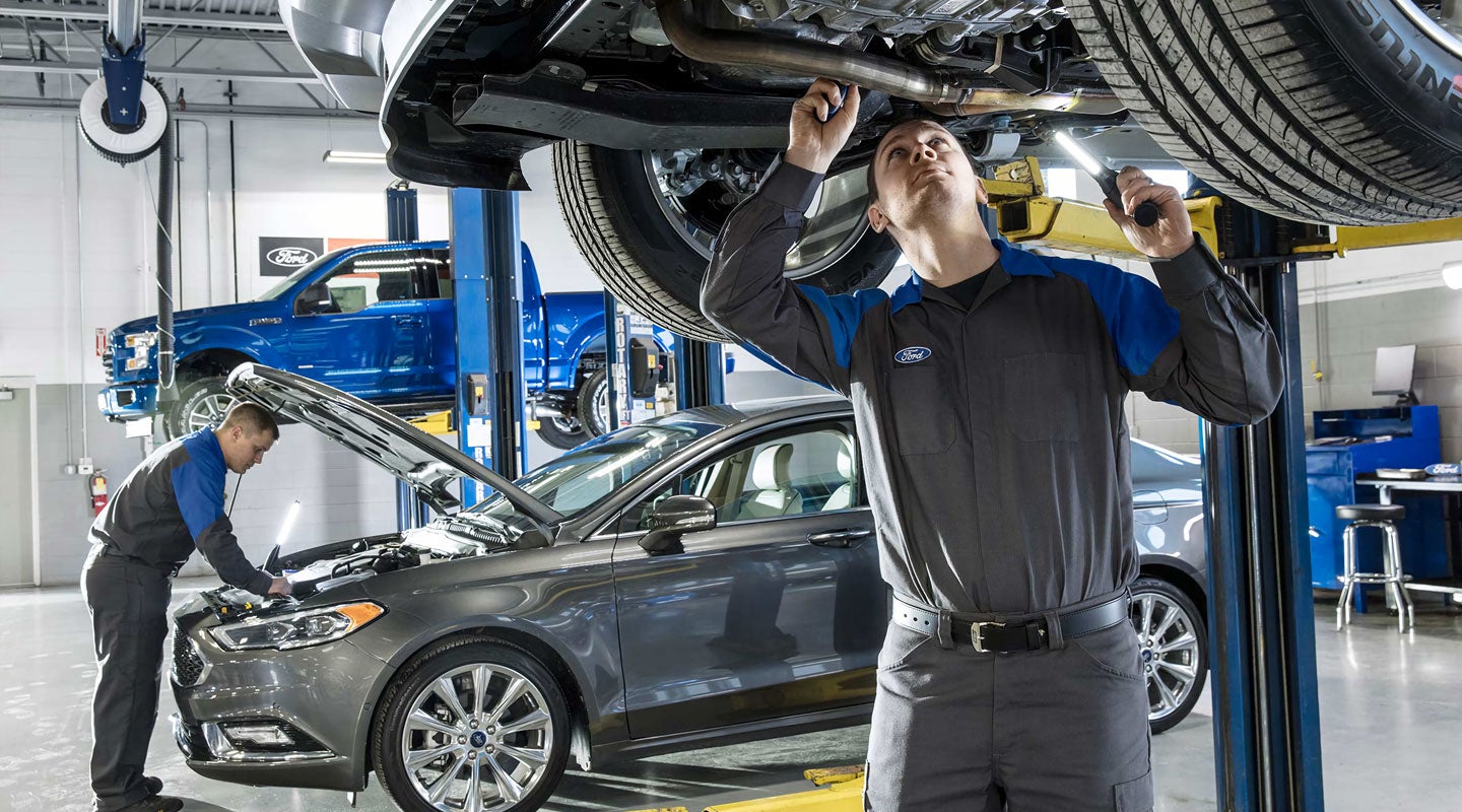 Technicians inspecting vehicles at a Ford service center