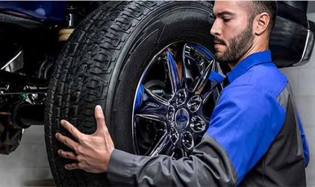 Technician installing a tire on a vehicle at a Ford service center